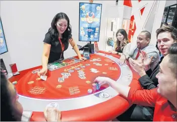  ?? Eduardo Contreras San Diego Union-Tribune ?? A GROUP OF PEOPLE play Gamblit Poker Live with Christine Angeles as dealer during the Indian Gaming Convention in San Diego this month. It’s made by Gamblit Gaming, a Glendale-based start-up.