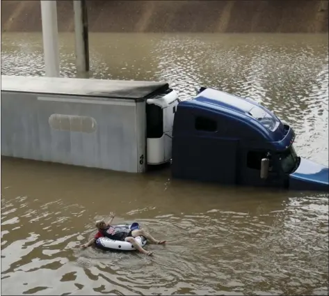  ?? AP PHOTO/CHARLIE RIEDEL ?? After helping the driver of the submerged truck get to safety, a man floats on the freeway flooded by Tropical Storm Harvey on Sunday, near downtown Houston.