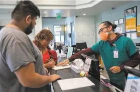  ?? LiPo Ching / Special to The Chronicle ?? Foothill Community Health Center medical aide Edwin Moreno wears a face mask while assisting Jose Hernandez (left) and Antonia Hernandez in San Jose.