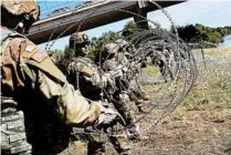  ?? JOHN MOORE/GETTY ?? U.S. Army active-duty troops from Fort Riley, Kan., lay out razor wire along the Rio Grande at the U.S.-Mexico border on Friday.