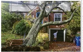  ?? ALANNA DURKIN RICHER / ASSOCIATED PRESS ?? A toppled tree leans onto a power line after an overnight storm Monday in Brookline, Mass. Trees also fell onto homes and vehicles in the region, but no serious injuries were reported. Hundreds of schools were forced to close.