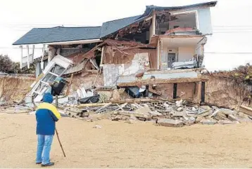  ?? PETER WILLOTT/AP ?? A beach walker watches as an abandoned beachfront home collapses due to beach erosion in Ponte Vedra Beach on Florida’s Atlantic Coast. The St. Johns Sheriff's Office posted pictures of the home on Facebook Wednesday, shortly after the structure began...