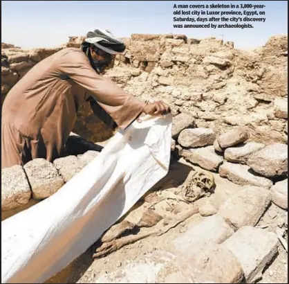  ??  ?? A man covers a skeleton in a 3,000-yearold lost city in Luxor province, Egypt, on Saturday, days after the city’s discovery was announced by archaeolog­ists.