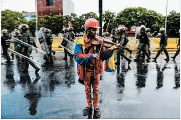  ?? FEDERICO PARRA/GETTY-AFP ?? Opposition demonstrat­or Wuilly Arteaga plays a violin during a May protest in Caracas against President Nicolas Maduro.