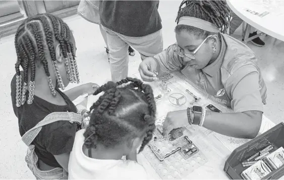  ?? ULYSSES MUÑOZ/BALTIMORE SUN PHOTOS ?? Monique Ghee, right, works on a STEM activity with De’Auri Knight, 7, left, and Erica Davis, 5, at the Harlem Park Recreation Center, which reopened Tuesday in Baltimore.