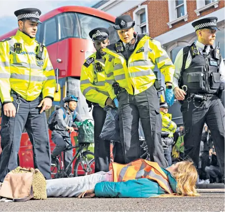  ?? ?? Coming unstuck Members of Just Stop Oil, the environmen­tal protest group, are detained by police after disrupting traffic when they blocked Islington Green and Upper Street, in north London, yesterday.