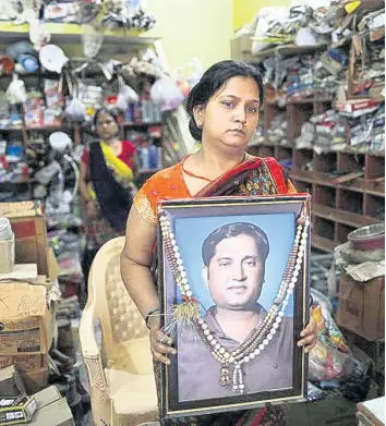  ?? AP ?? Reena Kesarwani holds a photograph of her husband, Anand Babu Kesarwani, who died of COVID19 in the Chhitpalga­rh village in India’s northern Uttar Pradesh state.