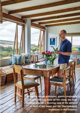  ?? ?? When the couple entertains, guests congregate around the long table on the stoep; the huge windows provide a stunning view of the wetland in front of the house and the Steenboksb­erg mountains in the distance.