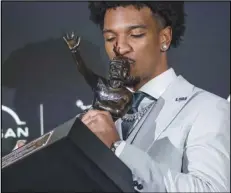  ?? Associated Press ?? LSU quarterbac­k Jayden Daniels kisses the Heisman Trophy during a news conference after winning the award on Saturday in New York.