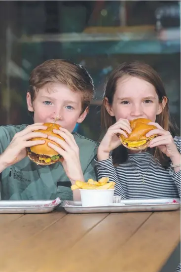  ?? Picture: ANNA ROGERS ?? YUM IN A BUN: Oliver Hales, 12, and his sister Emma, 9, enjoy their burgers from Evo Burger and experiment with their own at home.