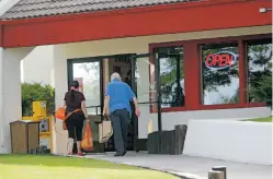  ?? LUIS SÁNCHEZ SATURNO/THE NEW MEXICAN ?? People walk into Weck’s on Monday. The owner of the restaurant defied the governor’s new shutdown order and kept his establishm­ent open.