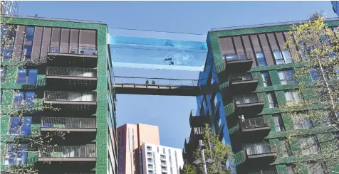  ?? JUSTIN TALLIS/AFP VIA GETTY IMAGES ?? A transparen­t acrylic swimming pool bridge is the first of its kind in the world, fixed 10-storeys up between two apartment blocks at Embassy Gardens in southwest London.