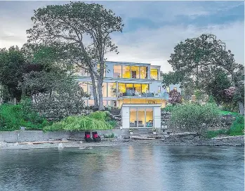  ??  ?? PHOTOS: JOSHUA LAWRENCE STUDIOS Left: The restoratio­n included installing wall-to-wall windows at the back overlookin­g the water, and opening the new great room on to a spacious new deck. The boathouse, foreground, was also rebuilt. Top right: The original front of the 1940s home was tired and run down.