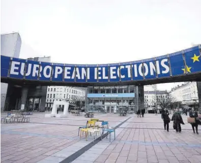  ?? VIRGINIA MAYO / AP ?? Un grupo de mujeres pasan junto a una pancarta que anuncia elecciones al Parlamento Europeo en junio.
