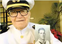  ?? (AP FOTO) ?? WW II VET. In this Dec. 5, 2016 photo, Jim Downing, 103, poses in a Navy uniform in Honolulu, with a photo of himself taken when he was about 20 years old. Downing is among a few dozen survivors of the Japanese attack on Pearl Harbor who plan to gather...