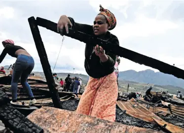  ?? | Ayanda Ndamane/Independen­t Newspapers ?? A KAYAMANDI informal settlement resident salvages what she can from her gutted shack.