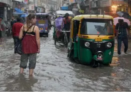  ?? — BIPLAB BANERJEE ?? People and vehicles (above) wade through a waterlogge­d road in New Delhi on Monday. A kid (right) enjoys himself after heavy rains lashed parts of the city on Monday.