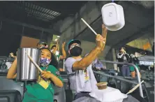  ??  ?? A’s fans Sofia Gonzalez, 5, and her father, Anthony, razz the Houston Astros by beating on garbage cans in the fifth inning.