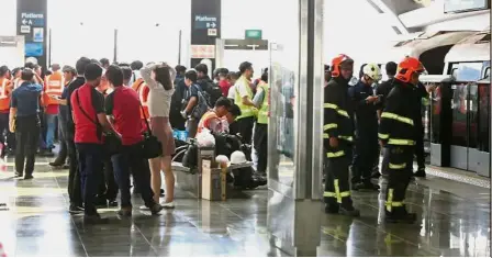  ??  ?? Not on track: Stranded commuters waiting around the Singapore MRT station as emergency personnel get to work to restore train services. — The Straits Times/Asia News Network