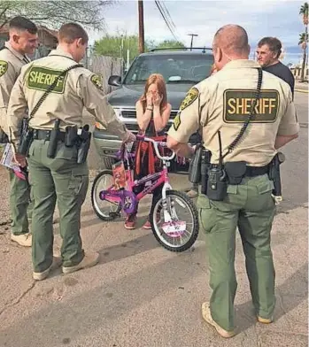  ?? PIMA COUNTY SHERIFF’S DEPARTMENT ?? Pima County sheriff’s deputies surprise a girl with a new bicycle on Tuesday after she had lost hers in a fire.
