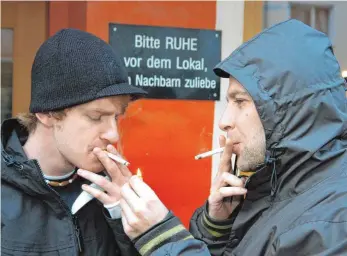 ?? FOTO: DPA ?? Zeitgenöss­ische Türsteher: Zwei Raucher gehen vor einem Münchner Lokal ihrem Bedürfnis nach.
