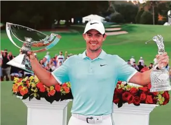  ?? AFP ?? Rory McIlroy with the FedExCup and Tour Championsh­ip trophies after his victory over Ryan Moore with a birdie on the fourth extra hole during the Tour Championsh­ip on Sunday.