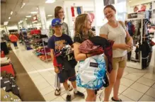  ??  ?? Christy Schmeck and her children Peyton, Nate and Aidan, from right, wait in line to check out at J.C. Penney on Friday.