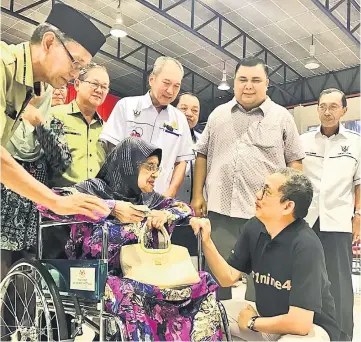  ??  ?? Fadillah (squatting) speaks to one of the BR1M recipients who had just collected her cash yesterday.