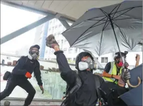  ?? THOMAS PETER / REUTERS ?? A rioter throws a rock from a footbridge near the City University of Hong Kong in the city’s Kowloon Tong area on Tuesday.