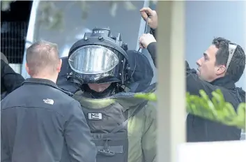  ?? MAL FAIRCLOUGH/GETTY IMAGES ?? A special operations officer puts on a bomb suit at the scene of a shootout in a Melbourne suburb on Tuesday. A man was killed in a gun battle with police during an hour-long standoff after taking a hostage Monday.