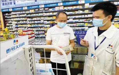  ?? ?? A licensed pharmacist (right) instructs a patient in choosing drugs at one of 111 Inc’s offline pharmacies in Guangzhou, Guangdong province, in November.