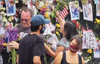  ?? Carl Juste / Associated Press ?? Volunteers along with locals replace dead flowers with fresh ones prior to the Guara family's burial at St. Joseph Catholic Church on Tuesday in Miami Beach, Fla.