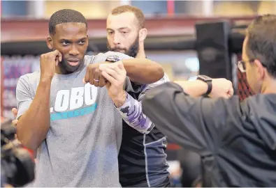  ?? ADOLPHE PIERRE-LOUIS/JOURNAL ?? UFC fighter Roman Dolidze, center, helps University of New Mexico men’s basketball assistant coach Jerome Robinson with his punching technique.