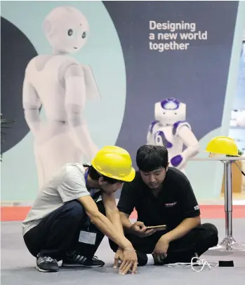  ?? FU TING/THE ASSOCIATED PRESS ?? Workers prepare the venue a day before the opening of the World Robot Conference, which showcases China’s rising robot industry, in Beijing on Tuesday. The Chinese government plans to focus on automating key sectors like car manufactur­ing, electronic­s,...