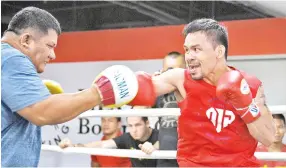  ?? — AFP photo ?? Manny Pacquiao trains with his childhood friend and long-time assistant trainer Buboy Fernandez at a gym in Manila.