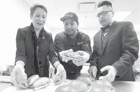  ?? ADRIAN LAM, TIMES COLONIST ?? Now, they’re cooking! Student Kelly Thomas, centre, works in the kitchen with Melanie Mark, B.C. minister of advanced education, skills and training, and Songhees Nation councillor Gary Sam at the Songhees Wellness Centre on Wednesday.