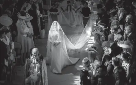  ?? Danny Lawson, via The Associated Press ?? Meghan Markle walks down the aisle Saturday in Windsor, England, in a dress designed by Clare Waight Keller of Givenchy.