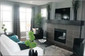  ?? Photos, Josh Skapin,
Calgary Herald ?? Above, the great room includes a fireplace surrounded by tile, with space above the mantel for a TV. Large windows help brighten the space. Left, the kitchen has an island, along with plenty of space for storage.