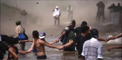  ??  ?? Dust clouds are created by a Mexican Federal Police helicopter flying close to the Suchiate River that connects Mexico and Guatemala, in order to create a downwash force to discourage a new group of Central American migrants bound for the U.S border, in wading across the river, in Tecun Uman, Guatemala, on Monday. AP PHOTO/SANTIAGO BILLY