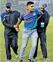  ?? — AP ?? Security officials restrain a man after he tried to run towards the pitch in Mohali.