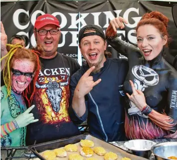  ?? Foto: Michael Bauer ?? Brot Sommelier Axel Schmitt (Zweiter von rechts) aus dem unterfränk­ischen Frankenwin­heim lässt sich in Wacken beim Backen von zwei Bodypainti­ng Models und einem Heavy Metal Fan helfen.