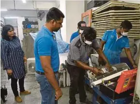  ?? (Foto Faiz Anuar /BH) ?? Goobi (dua dari kiri) dan Shymala (kiri) melihat pekerjanya menjalanka­n perkhidmat­an servis alat pendingin hawa di premis perniagaan­nya di Taman Bukit Pelangi, Shah Alam.