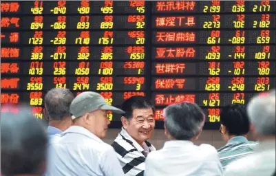  ?? SU YANG / FOR CHINA DAILY ?? Investors examine stock prices at a security brokerage in Nanjing, capital of Jiangsu province, on Wednesday.