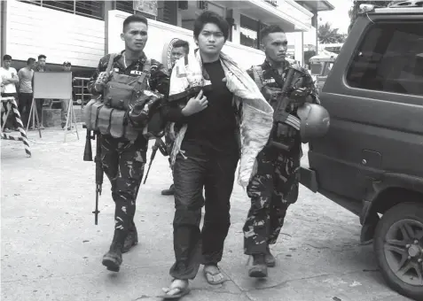  ?? AGENCE FRANCE PRESSE ?? This photo taken on August 23 shows soldiers escorting Maute extremist group member Hassim Balawag Maute alias Apple Jehad to a military vehicle in Marawi City a day after he and others were arrested at a military checkpoint. Jehad was among those who escaped in Saturday's daring jailbreak.