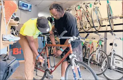  ?? SLADE RAND/HARTFORD COURANT ?? Joseph Dickerson, left, shows Richard Dixon, 43, how to attach a U-lock to the frame of the new bike he received through BiCi Co.’s “Bikes For Jobs” program on June 5.