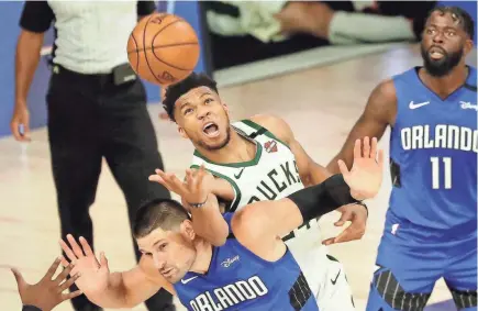  ?? KIM KLEMENT / USA TODAY SPORTS ?? Bucks forward Giannis Antetokoun­mpo fouls Magic center Nikola Vucevic while reaching for a loose ball Tuesday in Game 1 of the teams’ Eastern Conference playoff game.