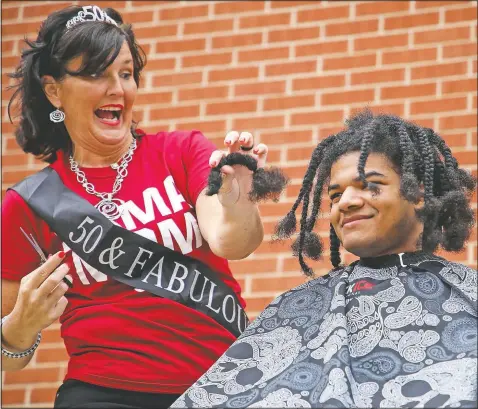  ?? (Courtesy Photo/Gregg Gelmis) ?? Family friend Amber Bray (left) cuts a braid from Kieran Moise’s hair during a public fundraiser held to donate his 19-inch hair to the nonprofit Children with Hair Loss in Huntsville,