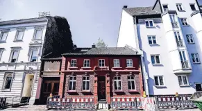  ??  ?? Klein und mit auffallend roter Fassade – das Haus wirkt, als hätten es seine Nachbarn in die Zange genommen.