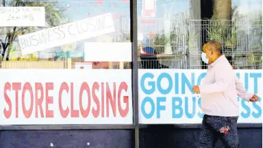  ?? AP ?? A man looks at signs of a closed store due to COVID-19 in Niles, Illinois, yesterday.