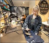  ?? AP/RICHARD DREW ?? Tailors Latoya Henderson (left) and Aly Reinert work in June in the Levi’s Tailor Shop in the Levi’s store in New York’s Times Square, a flagship store which has been reconfigur­ed from its original retail venue.